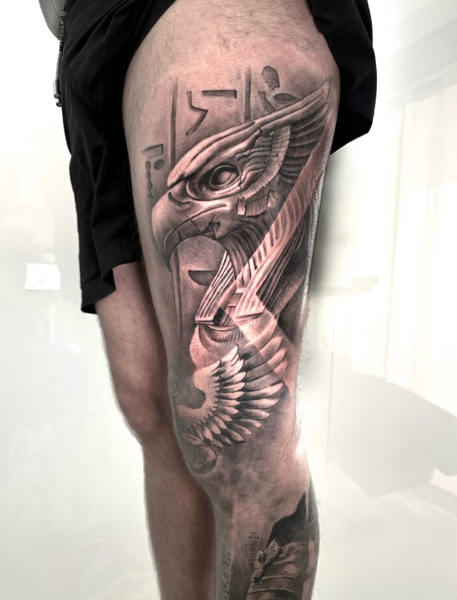 Tatuaje de ala y geometría en el muslo